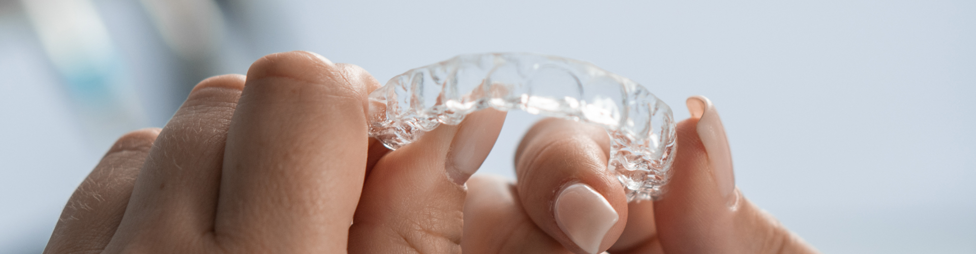 Close-up of a clear Invisalign aligner being held by a patient.
